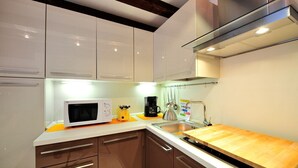 A modern kitchen with white cabinets, a microwave, a coffee maker, and a wooden countertop. - Creme Caramel Room by Wonderful Italy (Venecia)