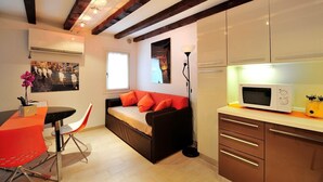 A compact living space with a sofa, dining table, and kitchenette. - Creme Caramel Room by Wonderful Italy (Venecia)