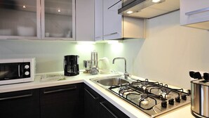 Eine moderne Küche mit Mikrowelle, Kaffeemaschine, Wasserkocher und Gasherd.