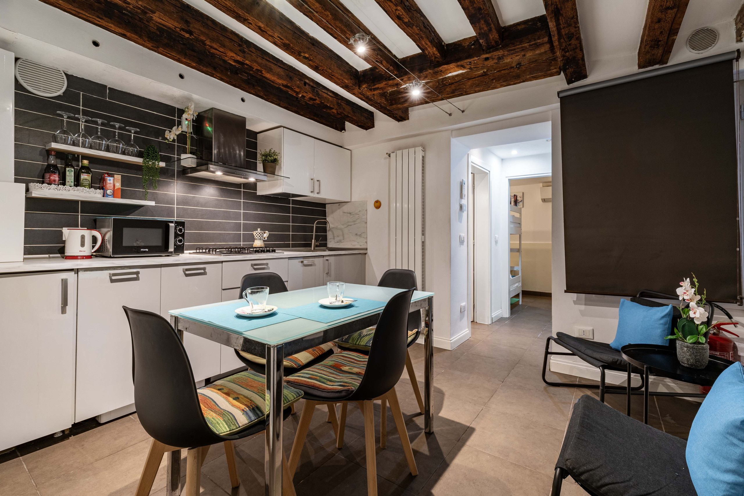 Cozinha moderna com área de jantar, incluindo mesa com cadeiras, cafeteira e micro-ondas.