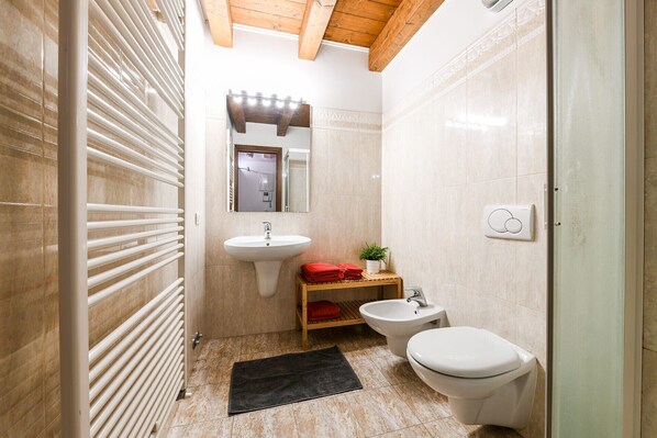 Un baño pequeño con inodoro, bidé, lavabo y toallero.