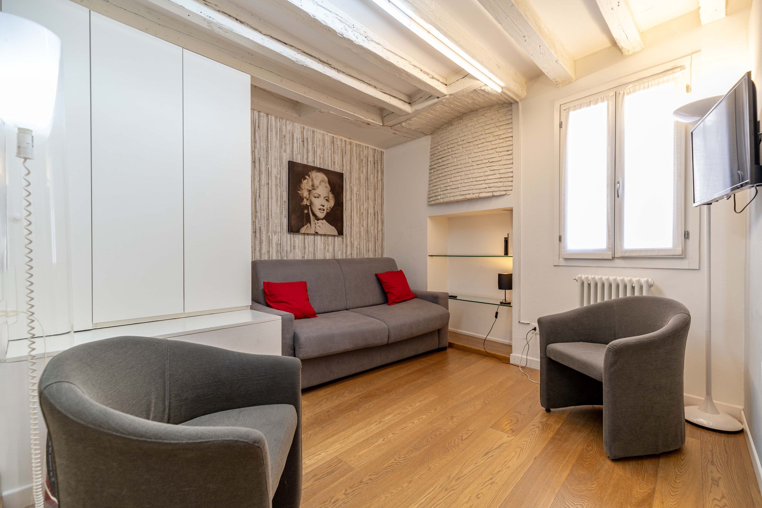 Ein modernes Wohnzimmer mit einer Couch, zwei Sesseln, einem Fernseher und einer Heizung.
