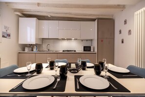 A modern dining area with a table set for four, kitchen cabinets, a microwave, and a radiator. - Pozzo Roverso by Wonderful Italy (Venecia)