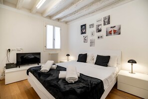 A bedroom with a bed, a desk with a computer, a window, and wall decorations.