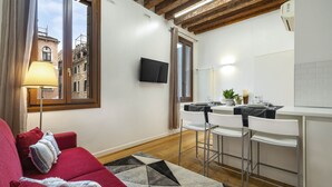 A modern living room with a red sofa, a patterned rug, and a dining area with white chairs and a table. - Ca' Beccarie 1 by Wonderful Italy (Venecia)