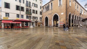 A spacious public square with a historic building featuring arched entrances and a tiled floor. - Ca' Beccarie 1 by Wonderful Italy (Venecia)