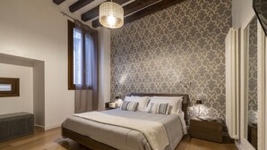 A bedroom with a large bed, wooden flooring, a patterned wallpaper, and a hanging light fixture. - Ca' Beccarie 1 by Wonderful Italy (Venecia)