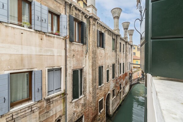 A narrow canal with buildings on either side, featuring arched windows and a traditional European architectural style.