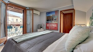 Ein Schlafzimmer mit einem Bett, einem Bild an der Wand und einem Balkon mit Tisch und Stühlen.
