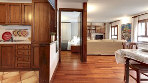 Ein geräumiges Wohnzimmer mit Holzböden, einer Couch, einem Esstisch und einer Küche mit Holzausstattung sowie einem Coca-Cola Kühlschrank.