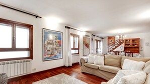 Ein geräumiges Wohnzimmer mit einem beigefarbenen Sofa, Holzböden und einer Treppe zu einer oberen Etage.