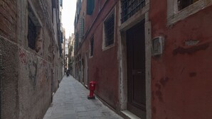 Une ruelle étroite avec un hydrant rouge, des bâtiments anciens et un chemin pavé.