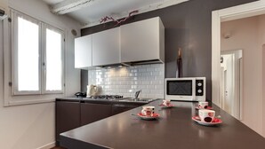 Une cuisine moderne avec un plan de travail foncé, des armoires blanches et un four à micro-ondes. On peut voir deux tasses sur le plan de travail.
