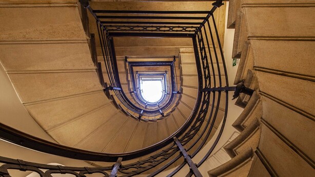 Eine Wendeltreppe, die zu einem Ausblick auf den Himmel führt.