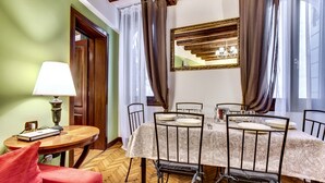 Ein Esszimmer mit einem runden Tisch, gedeckt für sechs Personen, umgeben von Stühlen und einer Lampe, sowie einem roten Sessel.