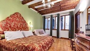 Ein Schlafzimmer mit einem großen Bett, Holzbalkendecke, einem Schminktisch und einem Fernseher.