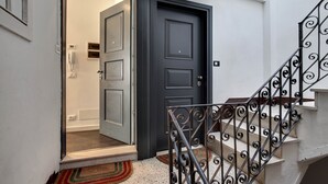 A staircase with ornate metal railings leading to a dark wooden door. - Biennale Apartment by Wonderful Italy (Venecia)
