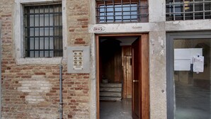 A building entrance with a wooden door and a metal gate, a staircase leading inside, and a sign above the door. - Biennale Apartment by Wonderful Italy (Venecia)
