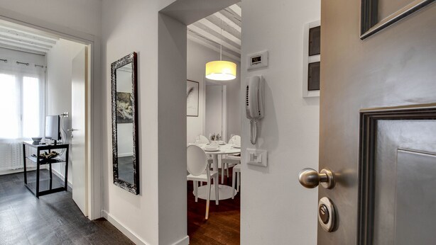 A modern interior with a dining area, a mirror, and a door leading to another room. - Biennale Apartment by Wonderful Italy (Venecia)
