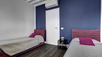 Una camera da letto con due letti, una porta bianca e un condizionatore d'aria.