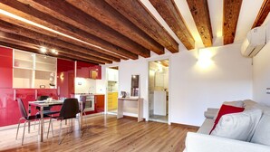 A modern living space with a wooden ceiling, a dining area with chairs and a table, and a white sofa with red cushions. - Residenza Valier by Wonderful Italy (Venecia)