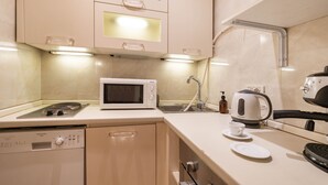 A compact kitchenette with a microwave, kettle, and a dishwasher.