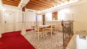 A dining area with white furniture, a red carpet, and a wooden ceiling.