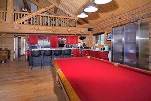 Un intérieur en bois comprenant une table de billard, une cuisine et un coin bar.