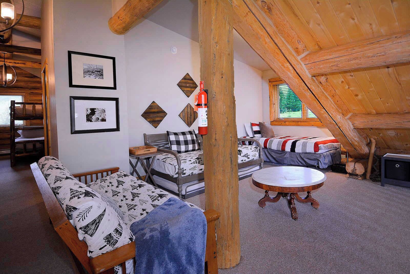 Un dormitorio estilo loft acogedor con techo de madera, una cama con ropa de cama estampada, un sofá y una mesa redonda.