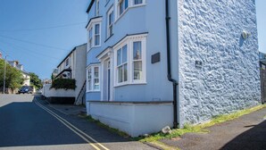A two-story building with a white facade and a blue textured wall on the right. There are no visible windows, doors, or other features. - Sea Glass - 2 Bedroom Apartment - Manorbier (Tenby)