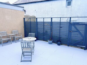Eine Terrasse mit Tisch und Stühlen, einem blauen Tor und einem Blumentopf.
