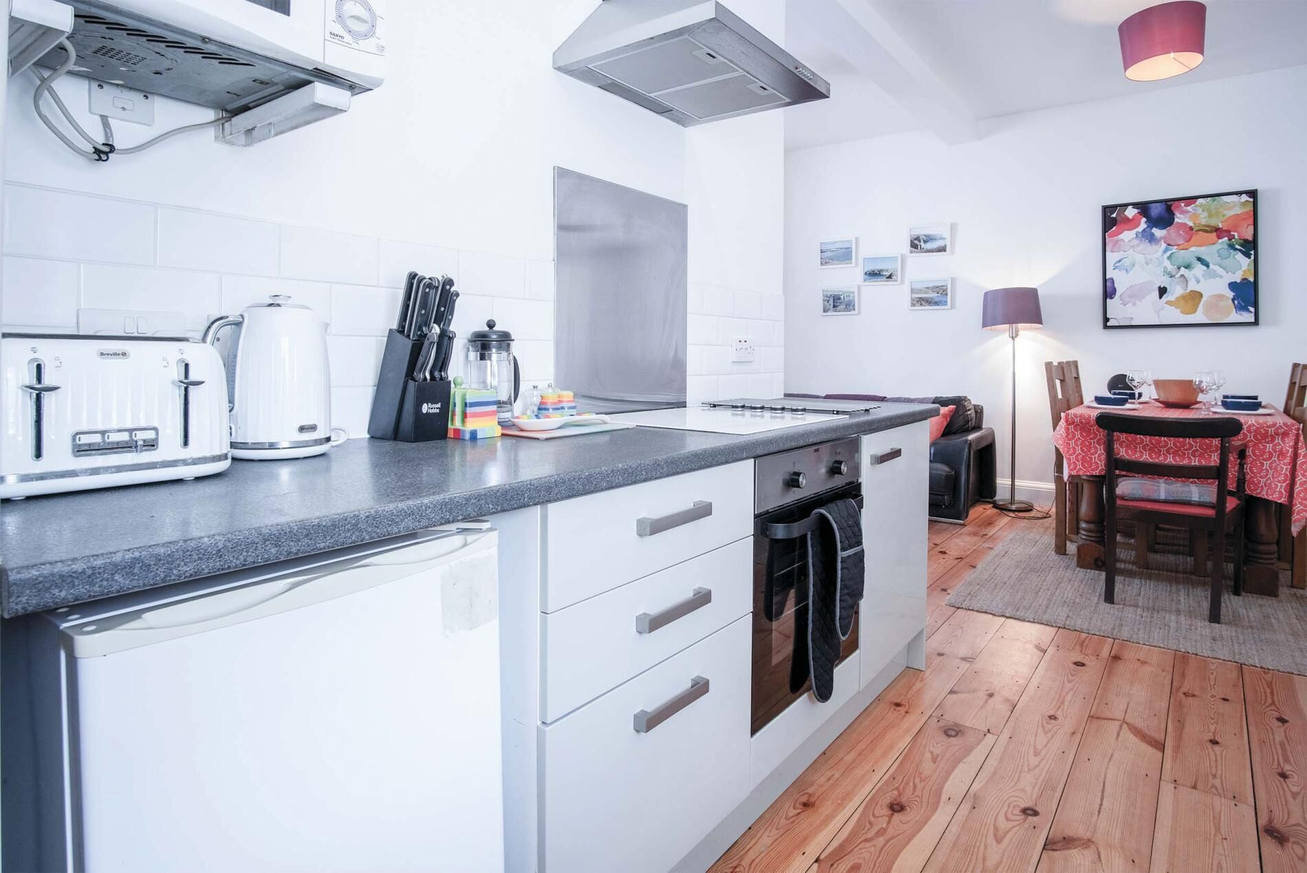A modern kitchen with white cabinets, a built-in oven, and a countertop with a coffee maker and toaster.