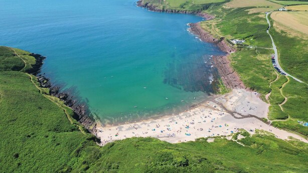 An aerial view of a coastal area with a beach, clear waters, and surrounding green fields. - Sea Glass - 2 Bedroom Apartment - Manorbier (Tenby)