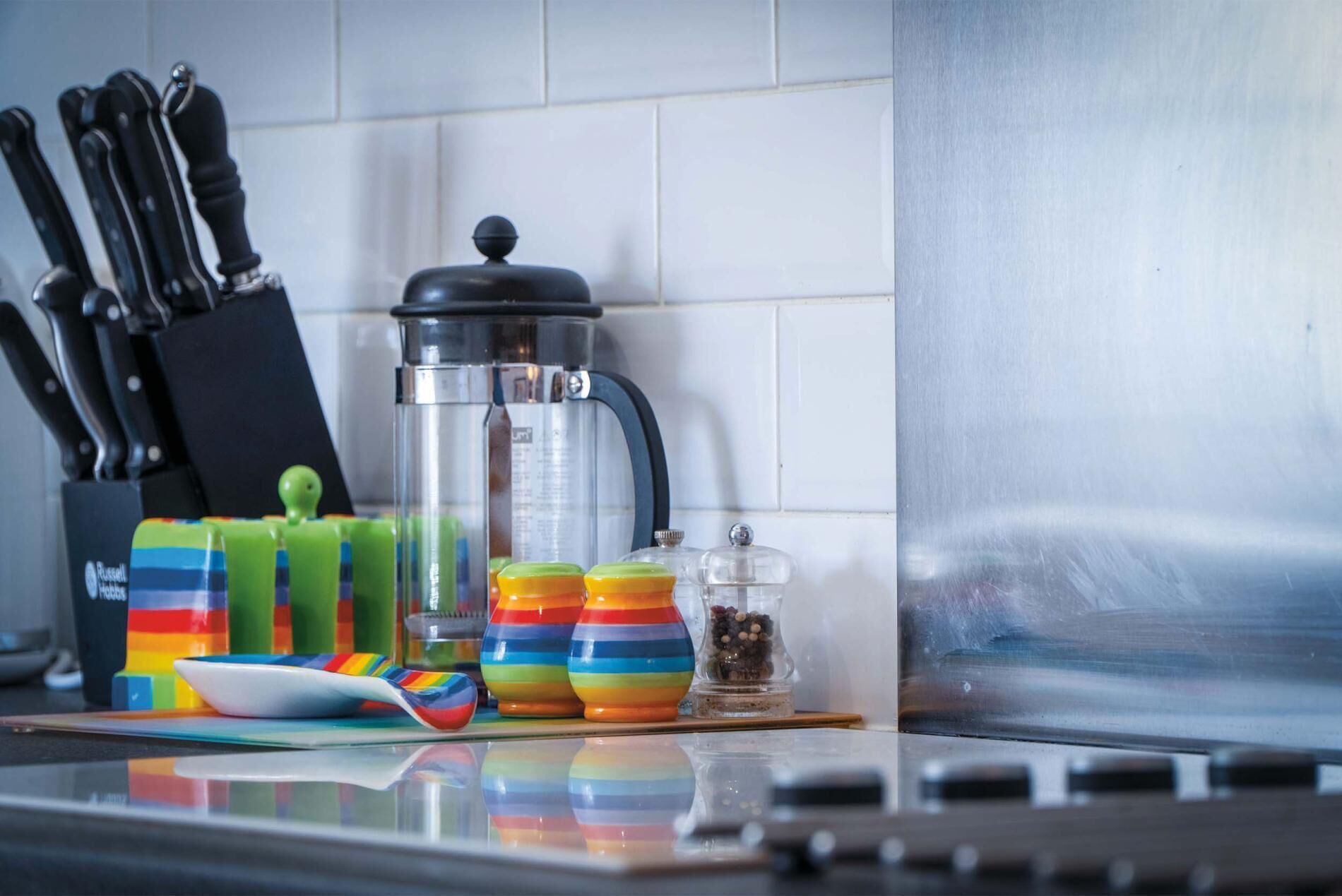 A kitchen counter with a coffee maker, colorful containers, and a knife set.