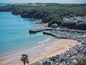 A coastal town with a sandy beach, a marina with boats, and residential buildings.