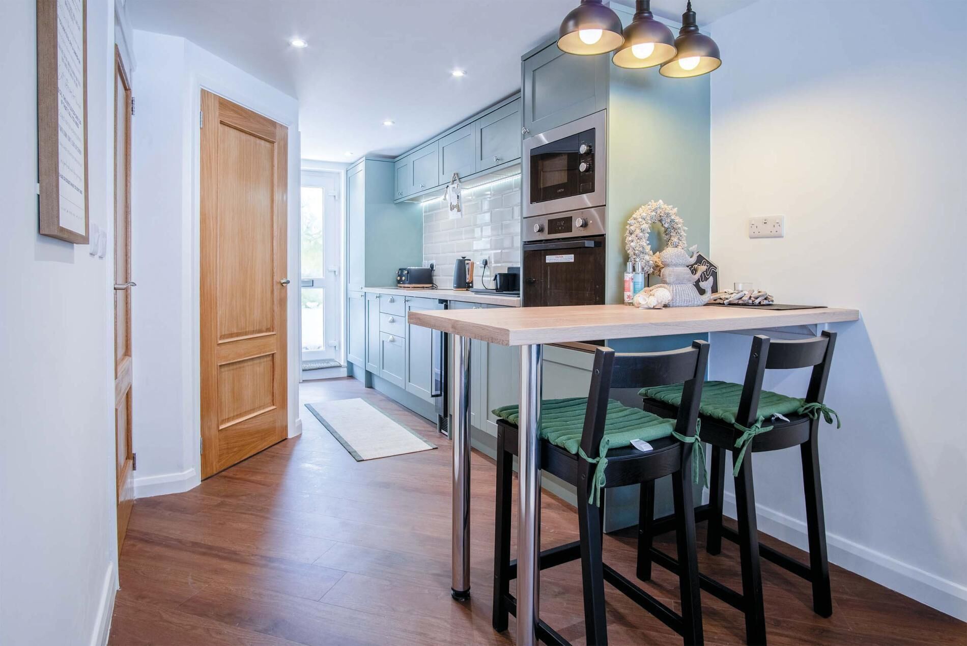 Una cocina moderna con puerta de madera, encimera y zona de comedor con sillas.