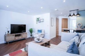 Relax in this stylish living room with a flat-screen TV, comfortable seating, and a dining area.