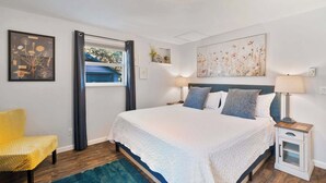 A bedroom with a large bed, bedside tables, a chair, and artwork on the walls. - Spacious Retreat with Hot Tub, Patio, & King Bed (Olympia)