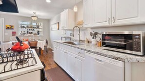 A kitchen with white cabinets, a gas stove, a microwave, and a coffee station. - Spacious Retreat with Hot Tub, Patio, & King Bed (Olympia)