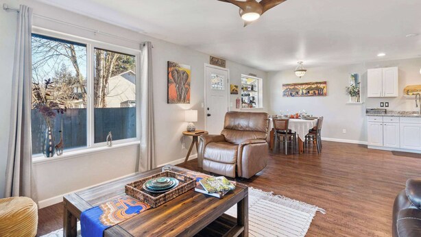A spacious living room with a dining area, a kitchen, and a ceiling fan. - Spacious Retreat with Hot Tub, Patio, & King Bed (Olympia)