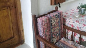 A wooden chair with a floral cushion, a table with a floral tablecloth, and a wooden door with a window. - Grandpa s Ouse in Tsagkarada (Zagora-Mouresi)