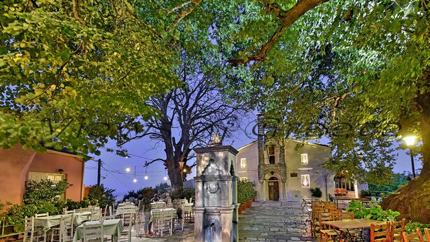 An outdoor dining area with stone tables and chairs, a central water feature, and a building in the background. - Grandpa s Ouse in Tsagkarada (Zagora-Mouresi)