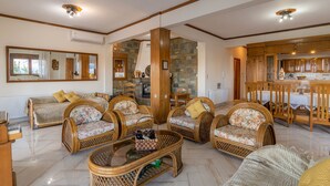 A spacious living room with wicker furniture, a large mirror, and a stone accent wall.