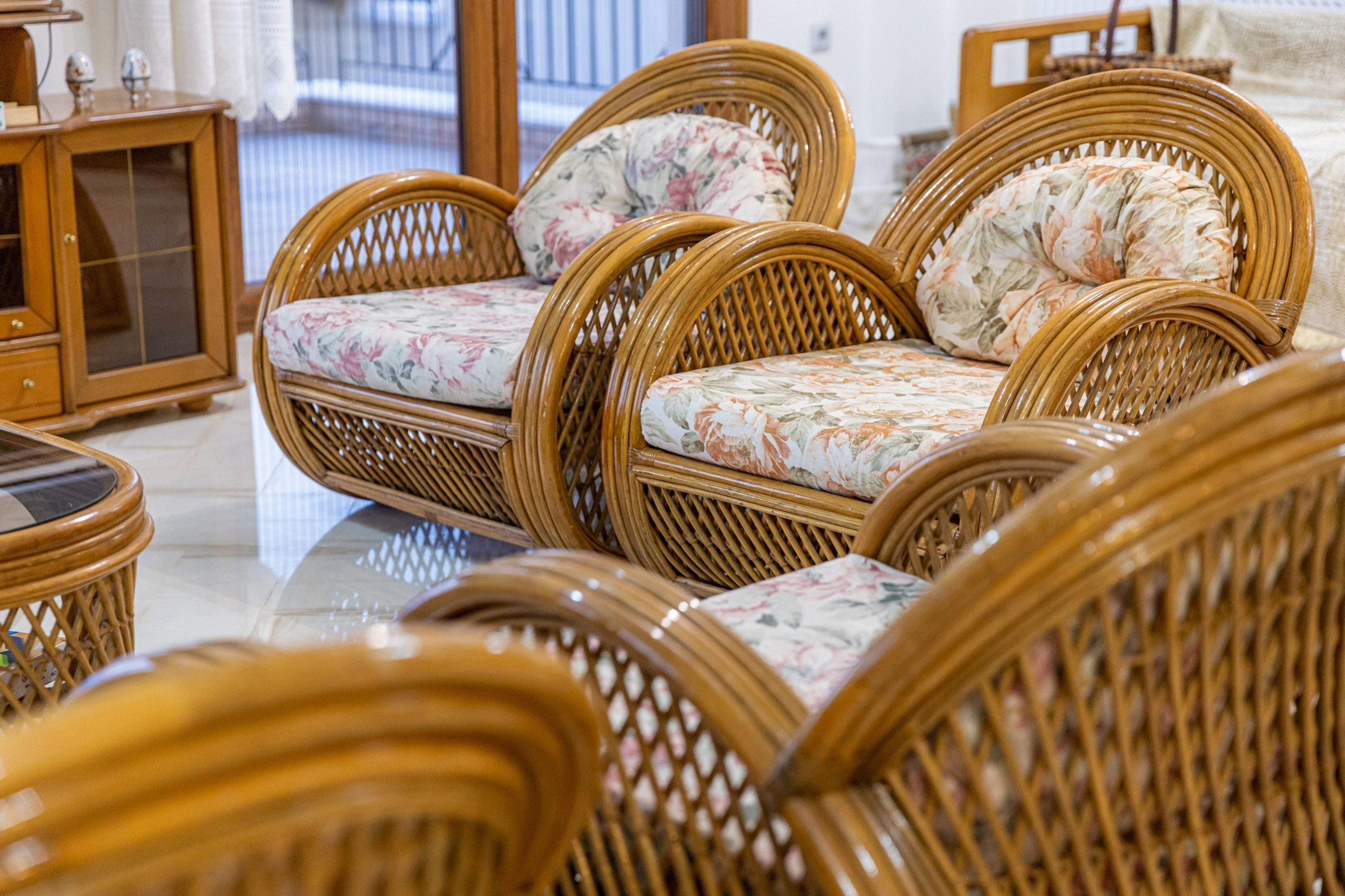 Wicker furniture with floral upholstery in a room with a tiled floor.