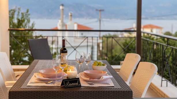 A table set for two with a view of the sea and mountains in the background.