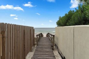 En träpromenad som leder till en strand med fri utsikt över havet.