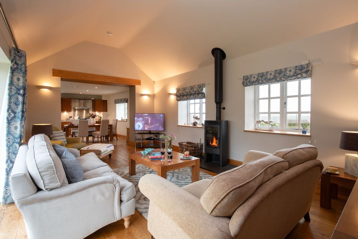 Spacious sitting room with comfortable sofas, log burner and French windows to the garden, barn conversion in Llanfaethlu, Anglesey