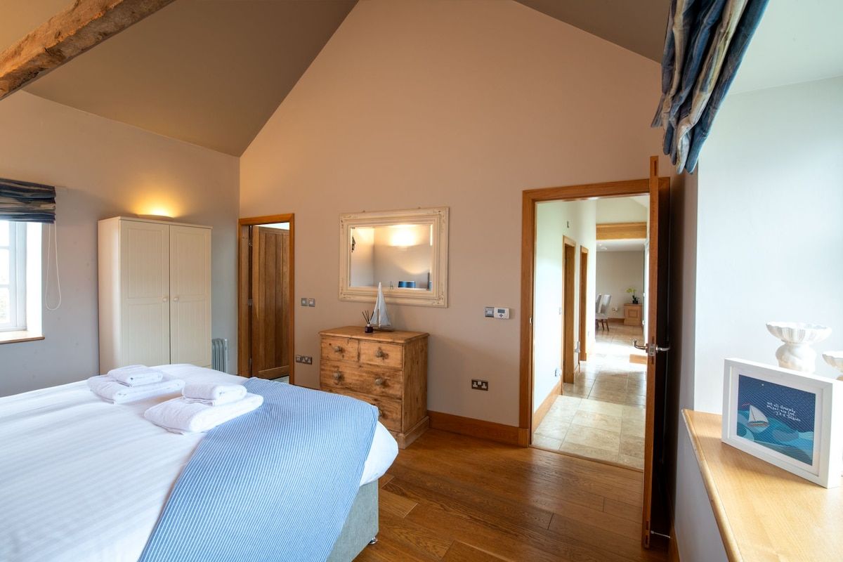 A bedroom with a bed, a dresser, a mirror, and a door leading to another room.