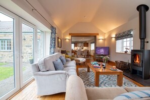 A spacious living room with a sofa, coffee table, and a fireplace. - No. 9 The Dairy: A beachside barn conversion on Anglesey (Llanfaethlu)
