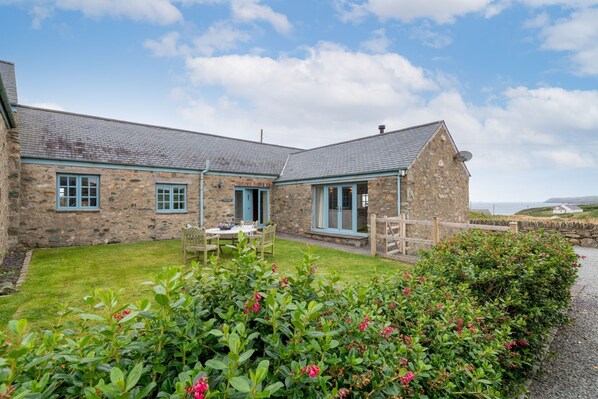 A stone building with a grassy yard and a wooden fence.